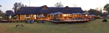 A lodge with multiple thatched-roof structures, outdoor seating areas, and a pool.