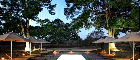 Una piscina al aire libre, sombrillas, sillones reclinables de piscina