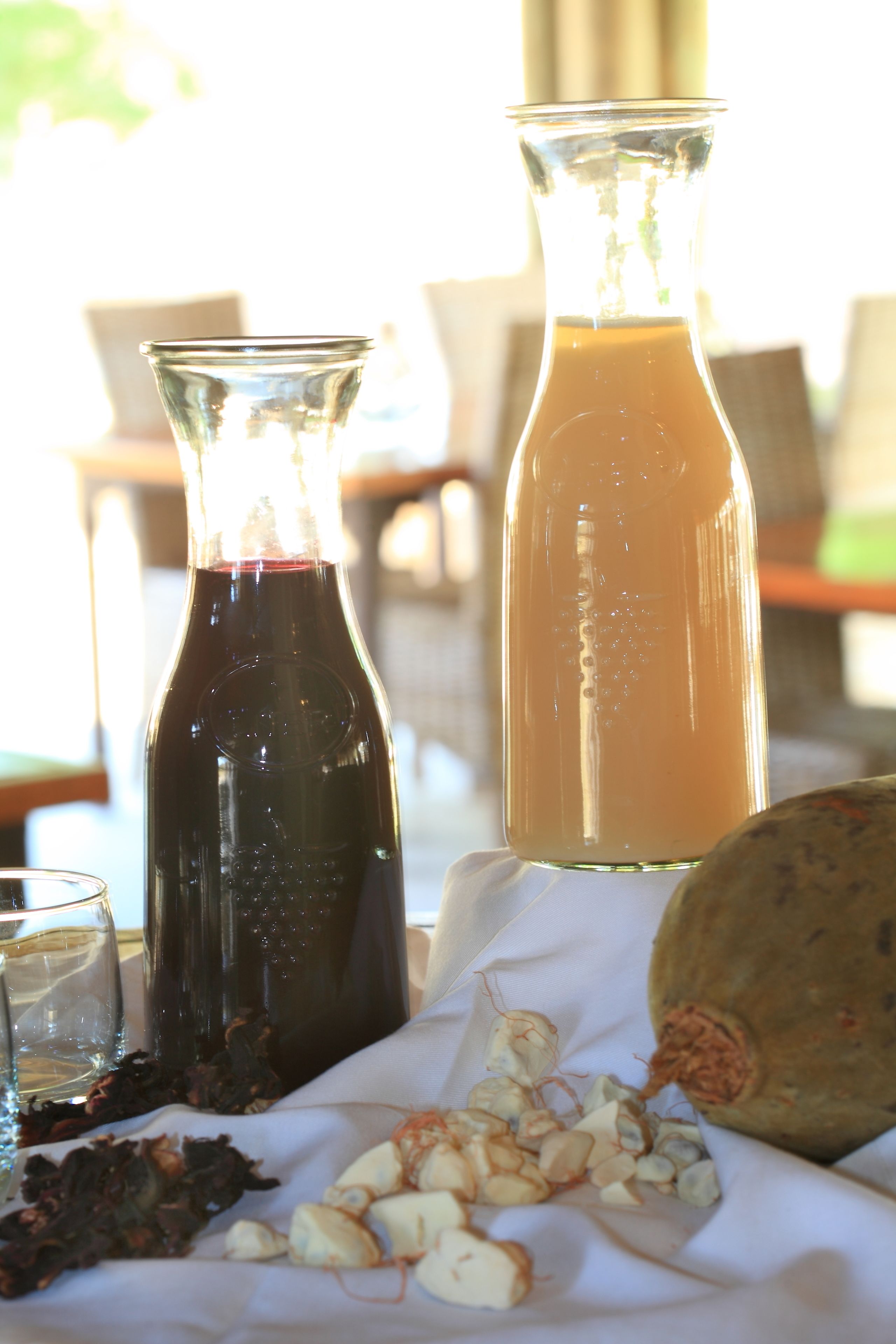 Two glass bottles on a table, one containing a dark liquid and the other a lighter liquid.