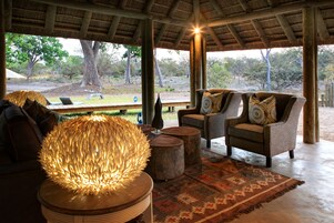 A covered outdoor seating area with two sofas, a round table, and a decorative light fixture.