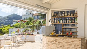 Un bar en la azotea con mesas al aire libre, una barra de ladrillo y estantes llenos de botellas de licor.