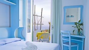 Una habitación de hotel con cama, escritorio y vista al mar.
