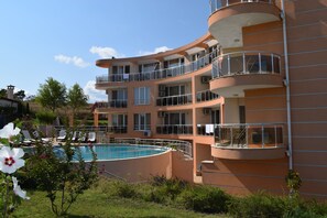 A multi-story hotel with a swimming pool, balconies, and a garden area. - Villa Orange (Sozopol)