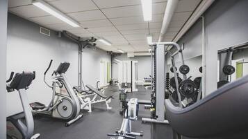 A gym with cardio machines, weightlifting equipment, and a digital display.