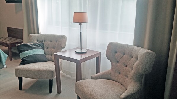A living room with two armchairs, a small table, and a floor lamp.