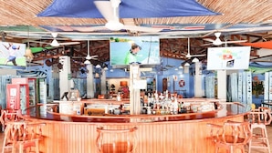 A bar area with a wooden counter, bar stools, and a ceiling fan. - Fish Hook Marina & Lodge (Golfito)