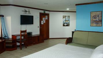Habitación de hotel con cama, escritorio con silla, televisión y obras de arte en las paredes.