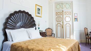 Une chambre à coucher avec un grand lit, un lustre et une porte ornée de panneaux décoratifs.