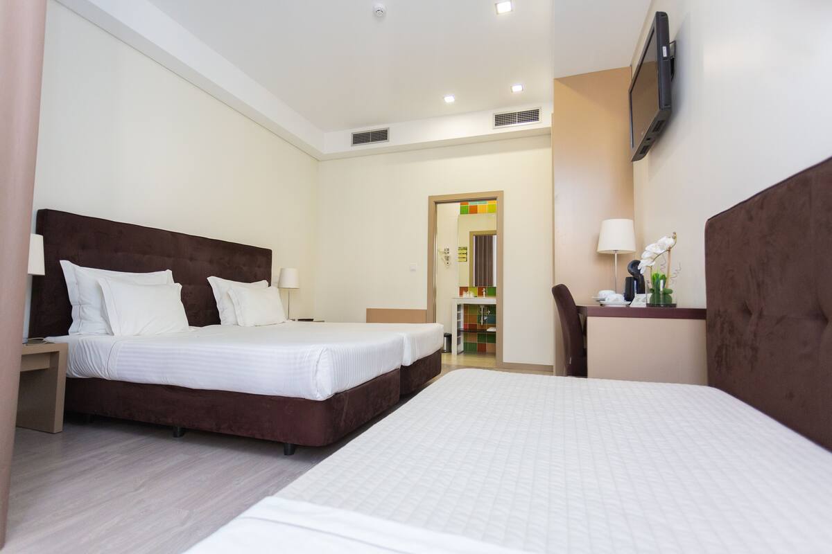 A hotel room with a large bed, a desk, and a TV mounted on the wall.