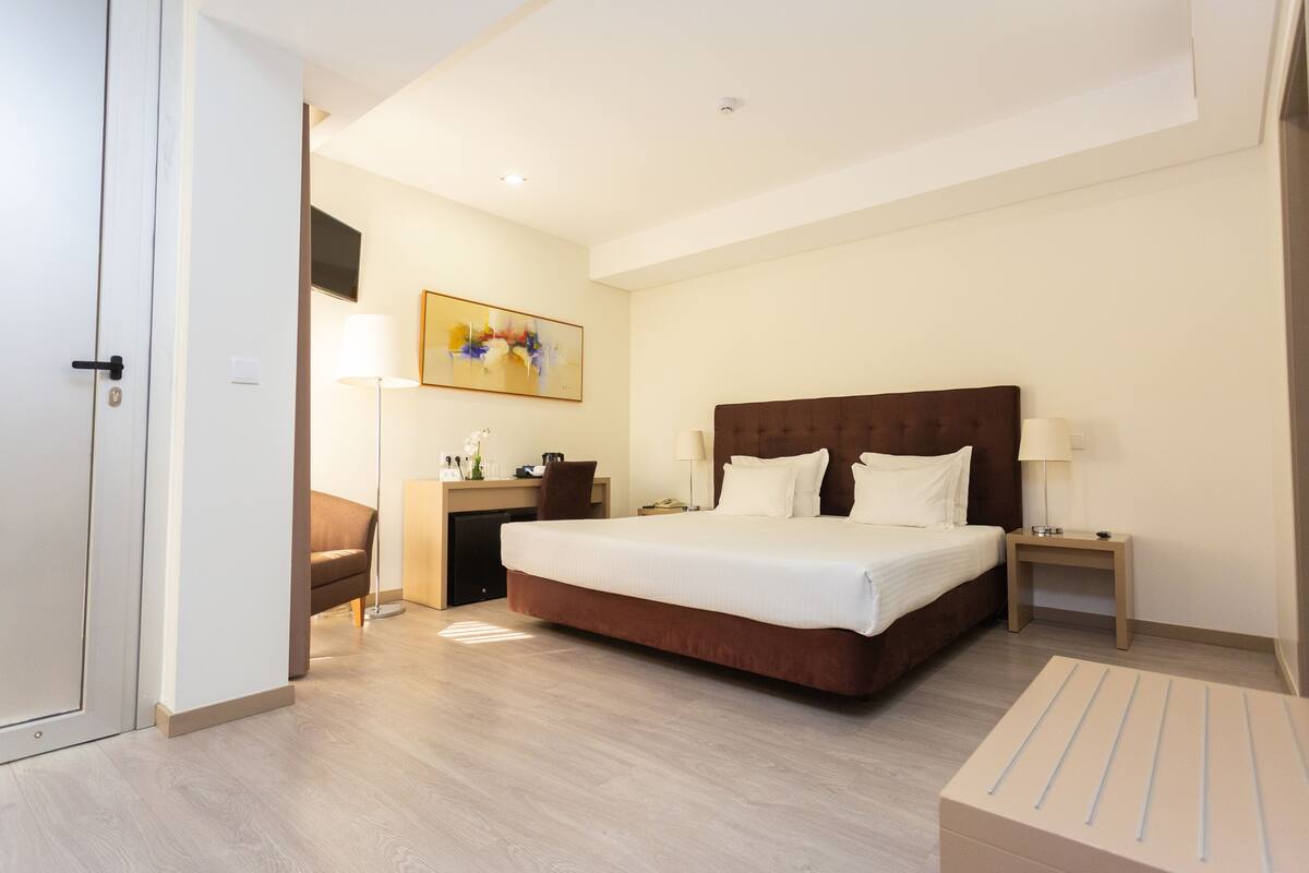 A hotel room with a large bed, bedside tables, a desk, and a chair.