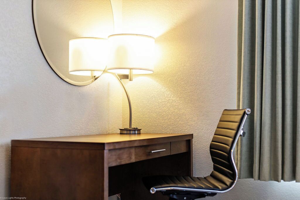 Een hotelkamer met een bureau, een stoel en een wandlamp.