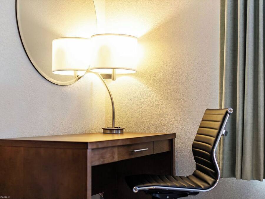 Een hotelkamer met een bureau, een stoel en een wandlamp.