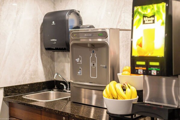 A modern kitchen with a water dispenser, a coffee machine, and a bowl of bananas. - Home Inn and Suites Lloydminster (Lloydminster)