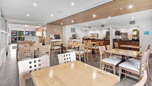 Un restaurante moderno con muebles de madera y una cocina visible al fondo.