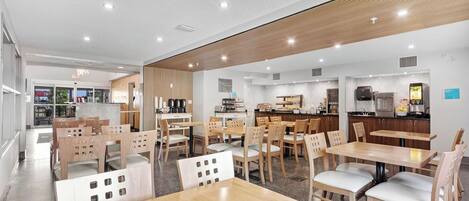 A modern restaurant with wooden furniture and a kitchen area visible in the background.