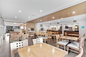 Un restaurante moderno con muebles de madera y una cocina visible al fondo.