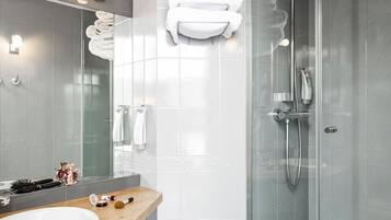 A modern bathroom with a large mirror, white tiles, a wooden vanity, and a glass shower enclosure.