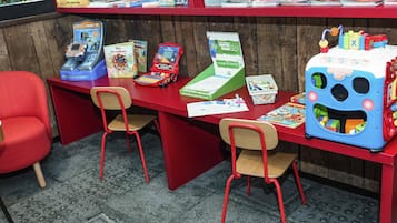 Un área de juegos infantiles con mobiliario rojo, juguetes educativos y libros.