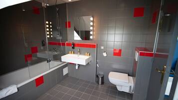 A modern bathroom with a glass-enclosed shower, a white sink, and a toilet.