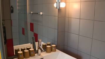 Un baño moderno con un lavamanos blanco, encimera roja y un espejo con luces arriba.