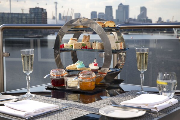 A table with a tiered dessert stand, two glasses of champagne, and a glass of water.
