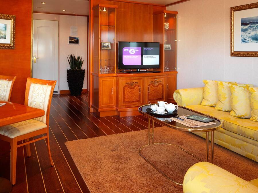 A living room with a yellow sofa, wooden coffee table, and a television on a wooden cabinet.