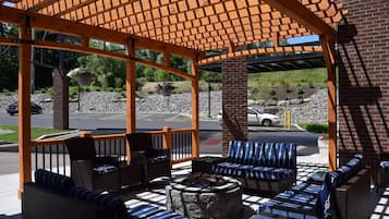 An outdoor seating area with wicker furniture and a stone fire pit.