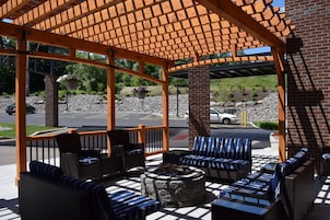 An outdoor seating area with wicker furniture and a stone fire pit.