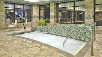 Un'area piscina interna con acqua cristallina, pareti piastrellate e una panca.