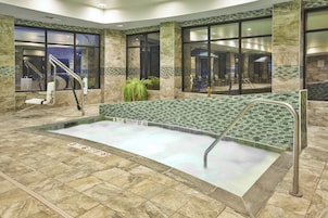 Un área de piscina interior con agua cristalina, paredes con azulejos y un banco.