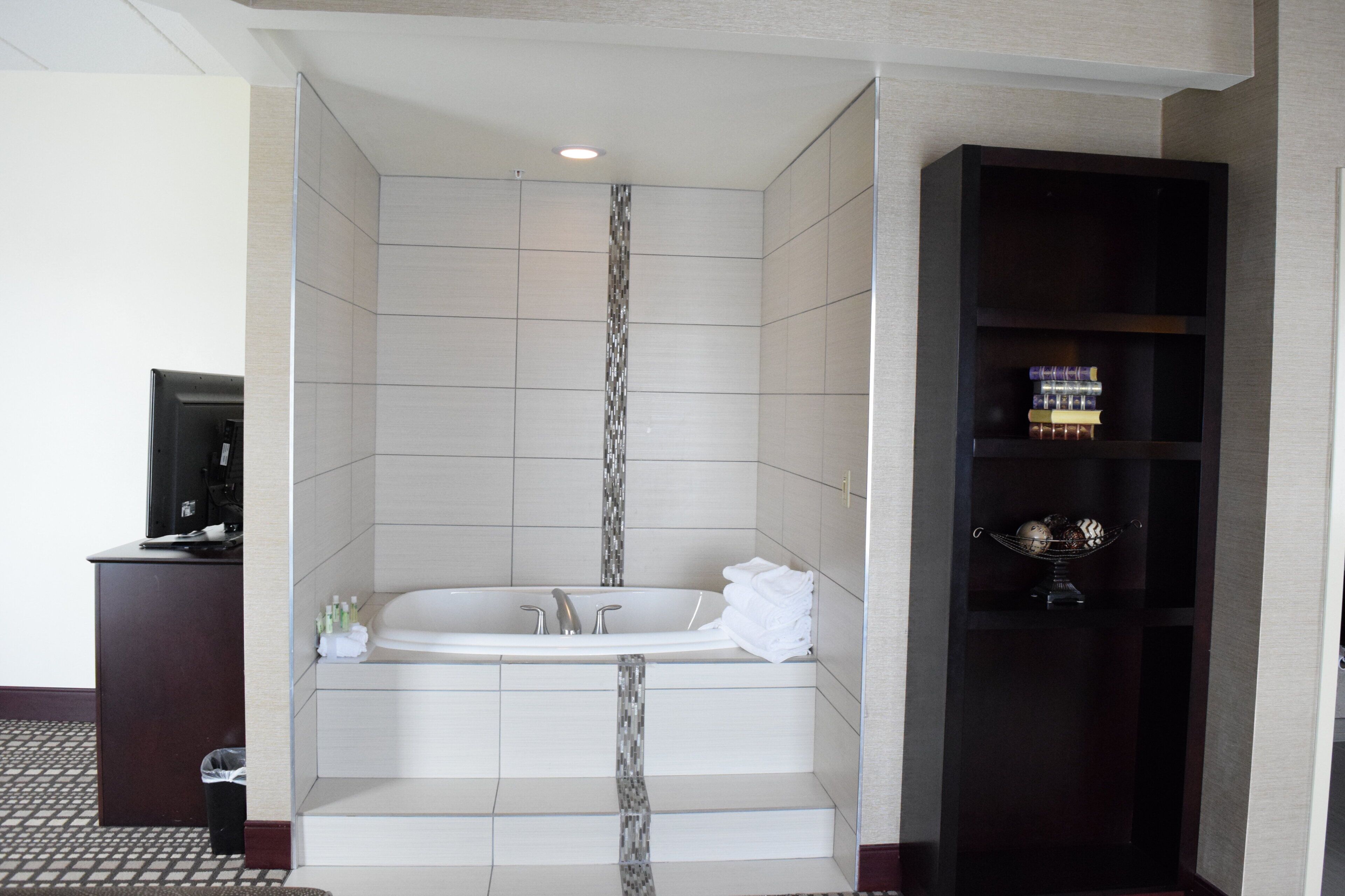 A modern bathroom with a freestanding bathtub, a vanity, and a shelf with toiletries.