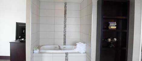 A modern bathroom with a freestanding bathtub, a vanity, and a shelf with toiletries.