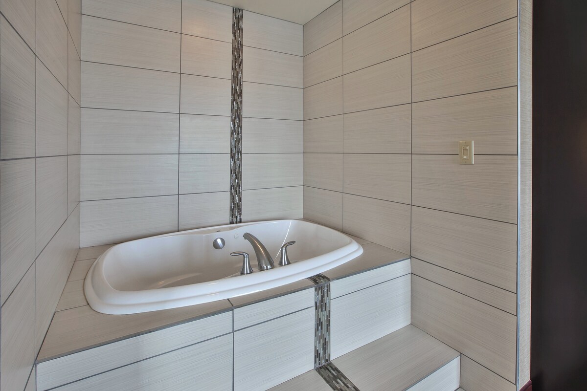 A bathroom with a freestanding bathtub, tiled walls, and a visible light switch.
