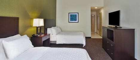 A hotel room with two beds, a desk, a television, and a painting on the wall.