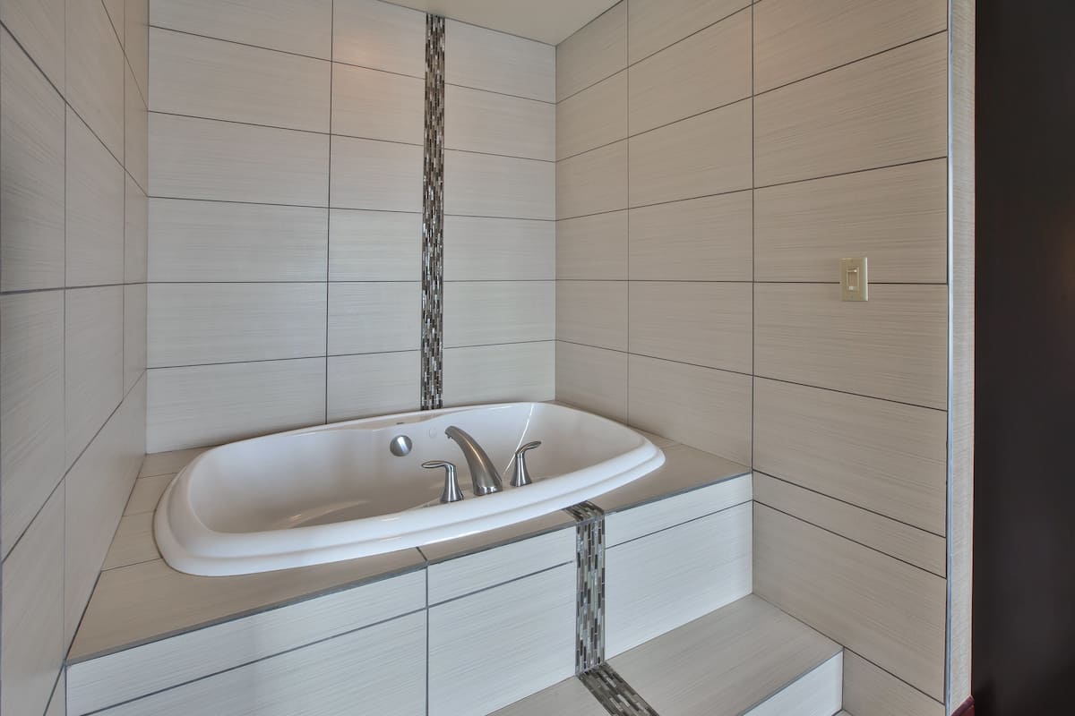 A modern bathroom with a freestanding bathtub, tiled walls, and a visible light switch.