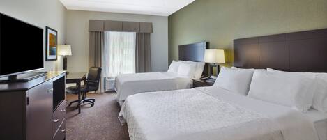 Een hotelkamer met twee bedden, een bureau, een televisie en een raam met gordijnen.