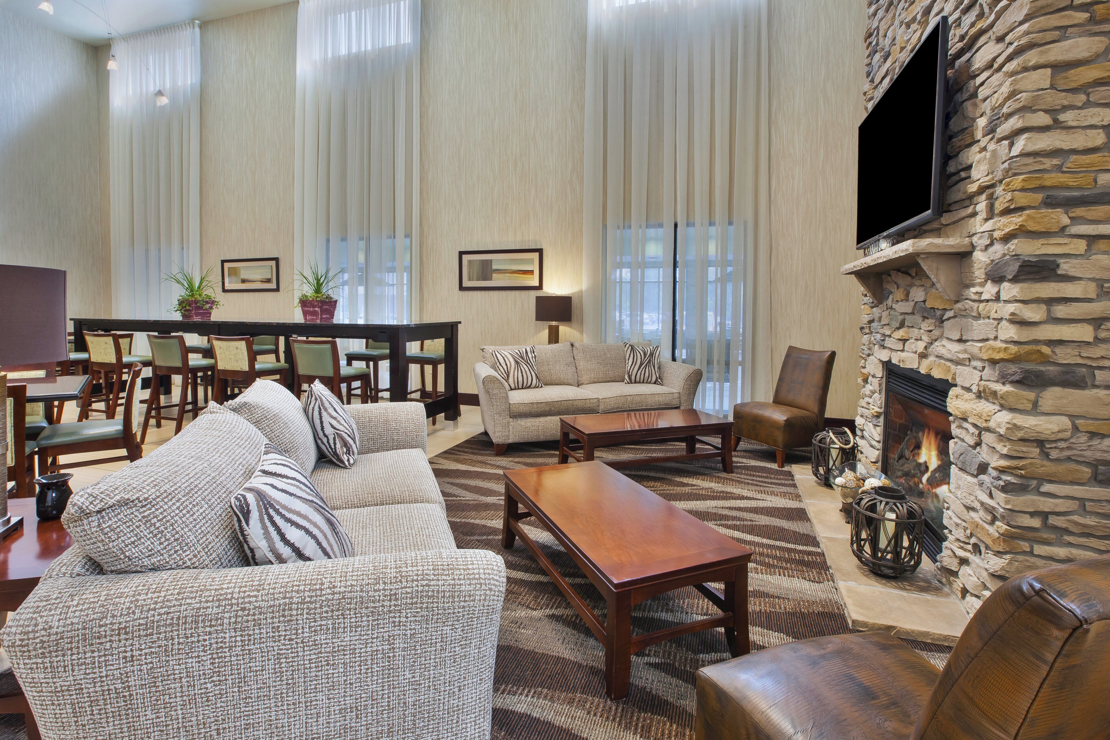 A spacious living room with a stone fireplace, a sofa set, a coffee table, and a dining area with chairs and a table.