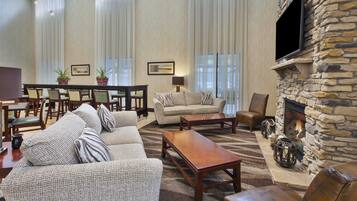 A spacious living room with a stone fireplace, a sofa set, a coffee table, and a dining area with chairs and a table.