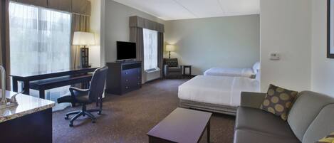 A hotel room with a bed, a desk, a chair, a sofa, and a television.