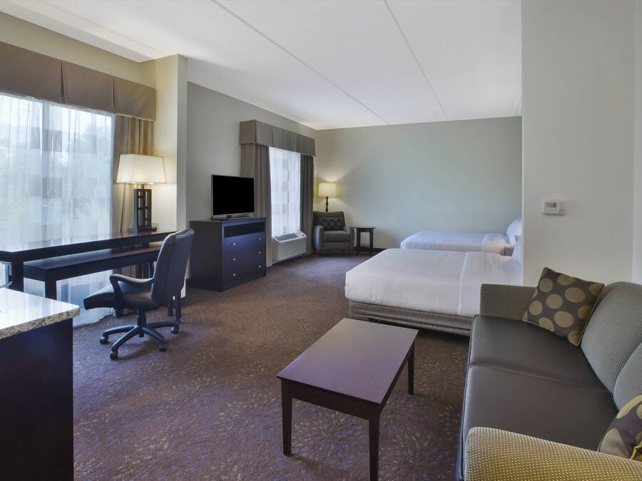 A hotel room with a bed, a desk, a chair, a sofa, and a television.