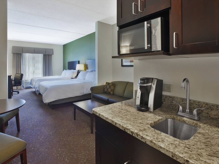 Quarto de hotel com cozinha compacta, cama, sofá e área de refeições.