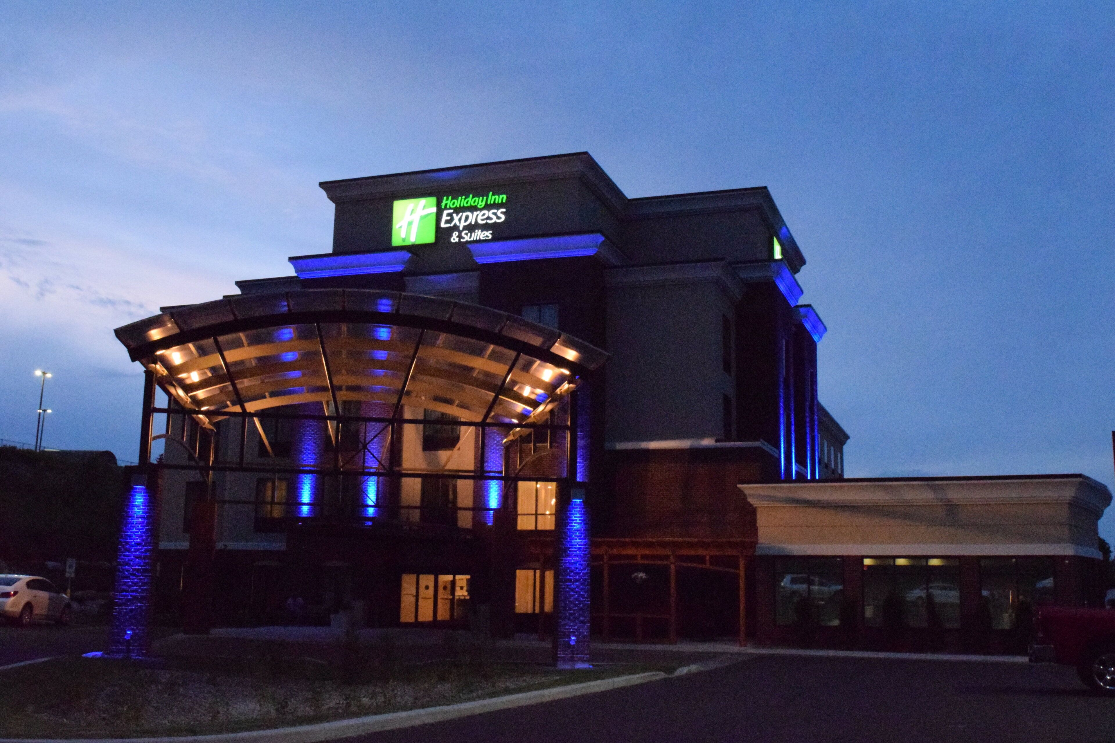 A Holiday Inn Express & Suites building with a glass entrance and illuminated signage.
