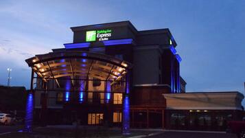 A Holiday Inn Express & Suites building with a glass entrance and illuminated signage.