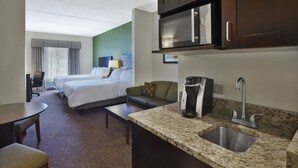 Une chambre d’hôtel équipée d’une kitchenette, d’un lit, d’un canapé, d’un bureau et d’une chaise.