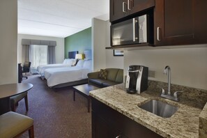 A hotel room with a kitchenette, a bed, a sofa, a desk, and a chair. - Holiday Inn Express & Suites Geneva Finger Lakes by IHG (Geneva)