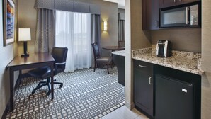 Une chambre d’hôtel équipée d’un coin repas, d’un four à micro-ondes, d’une machine à café et d’un bureau avec une chaise.