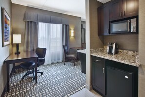 A hotel room with a dining area, a microwave, a coffee maker, and a desk with a chair. - Holiday Inn Express & Suites Geneva Finger Lakes by IHG (Geneva)