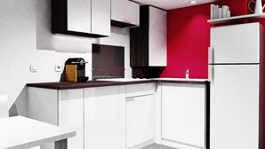 A modern kitchen with white cabinets, a red accent wall, and a built-in oven. - Nordsjællands Feriepark & Camping (Alsgarde)