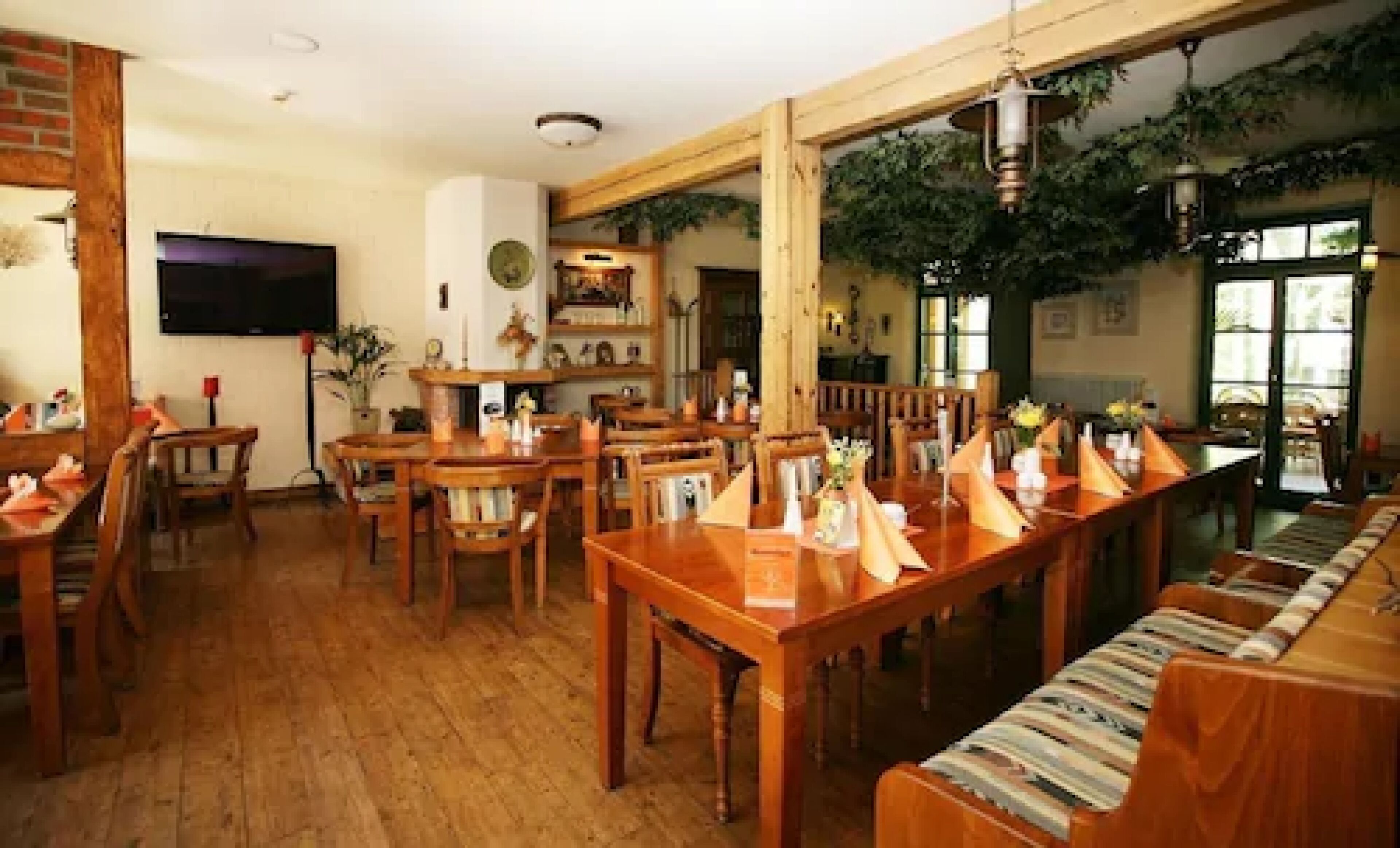 Un restaurante con mesas y sillas de madera, un televisor y una pared de ladrillo.