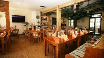 Un restaurante con mesas y sillas de madera, un televisor y una pared de ladrillo.